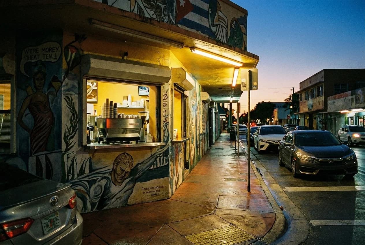 A ventanita walk-up coffee window on Calle Ocho in Little Havana at dawn, counter lit by overhead light