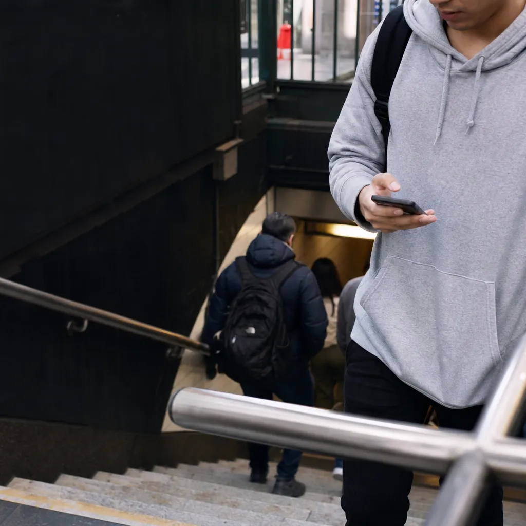 A student checking the time near a New York subway entrance before class