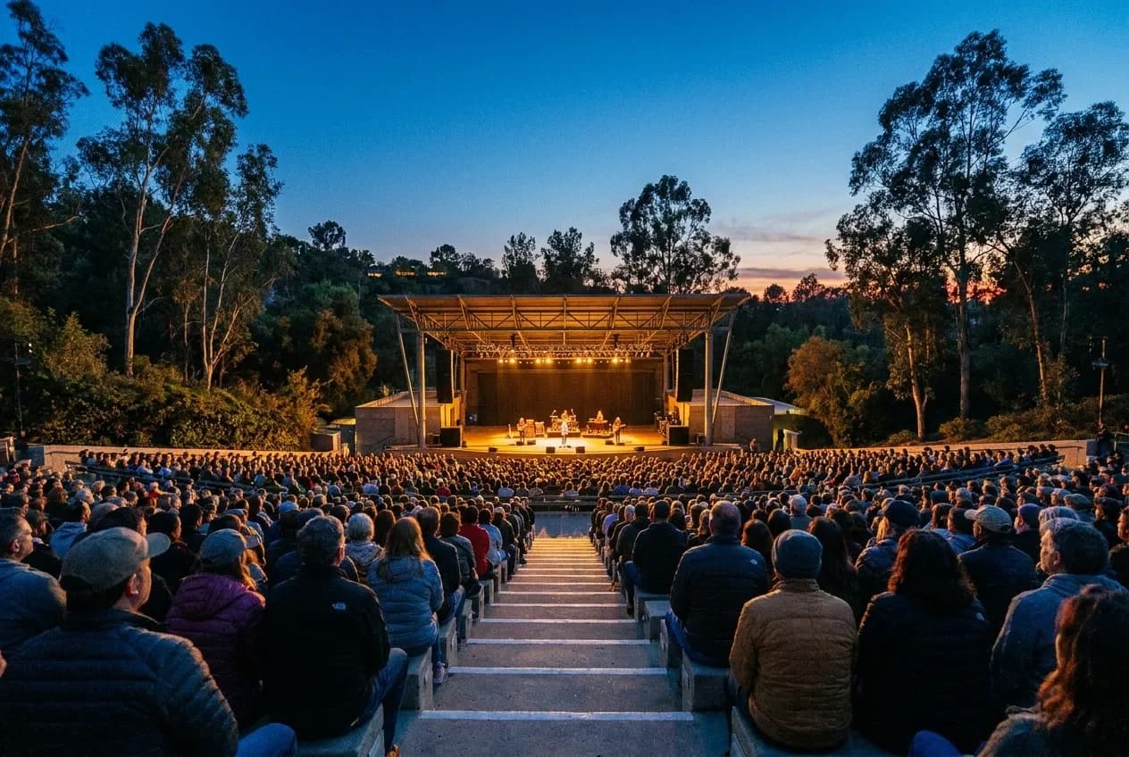 A small hillside amphitheatre at dusk with the stage lit and the audience seated