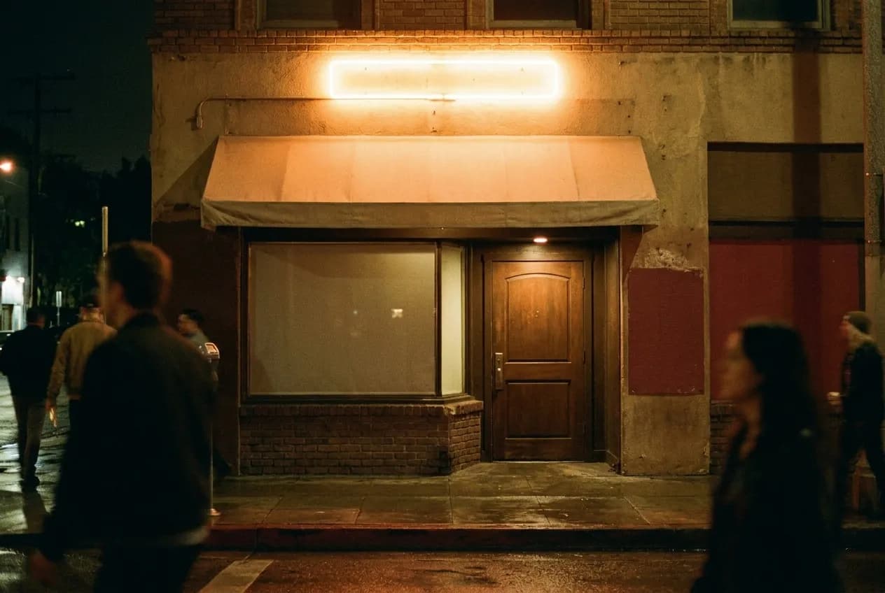A small club exterior at night with a low awning and a single neon glow