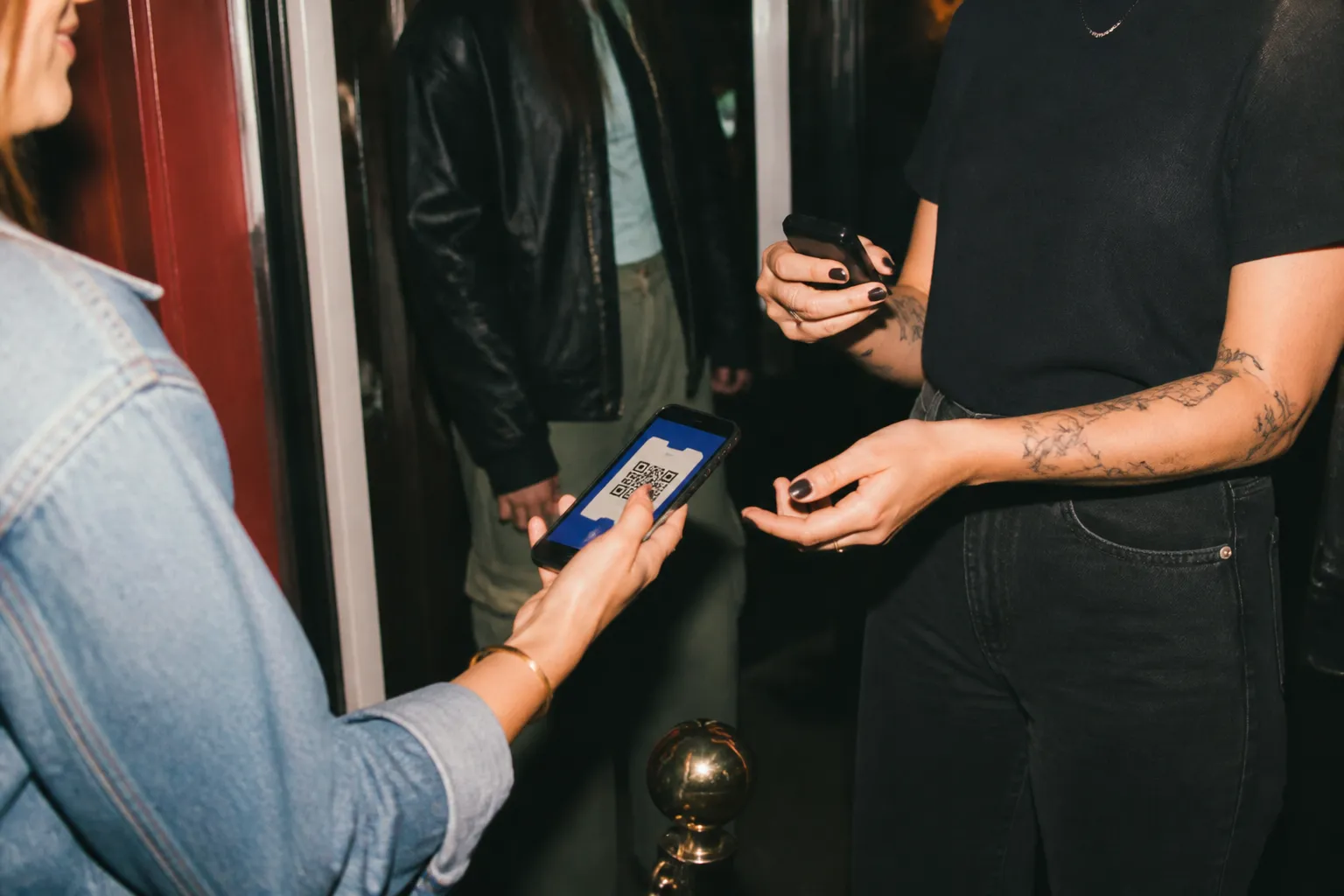 A phone displaying a digital event ticket held up at a venue entrance
