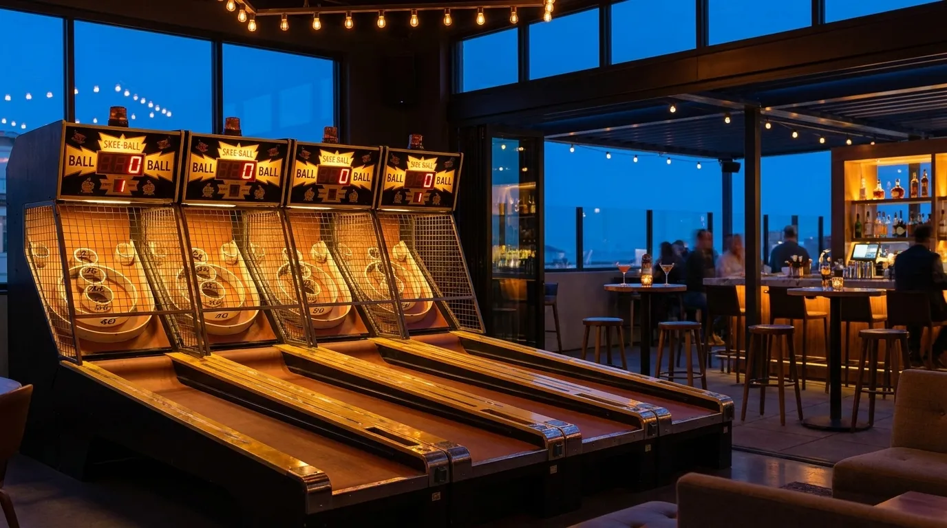 Regulation Skee-Ball lanes with glowing scoreboards in a modern arcade lounge, high-top tables and cocktail glasses visible in the background