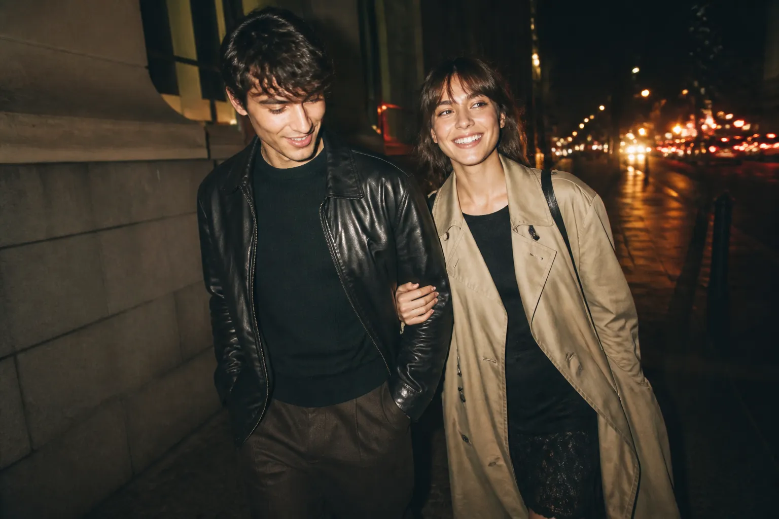 A couple strolling past softly lit city streets in the evening