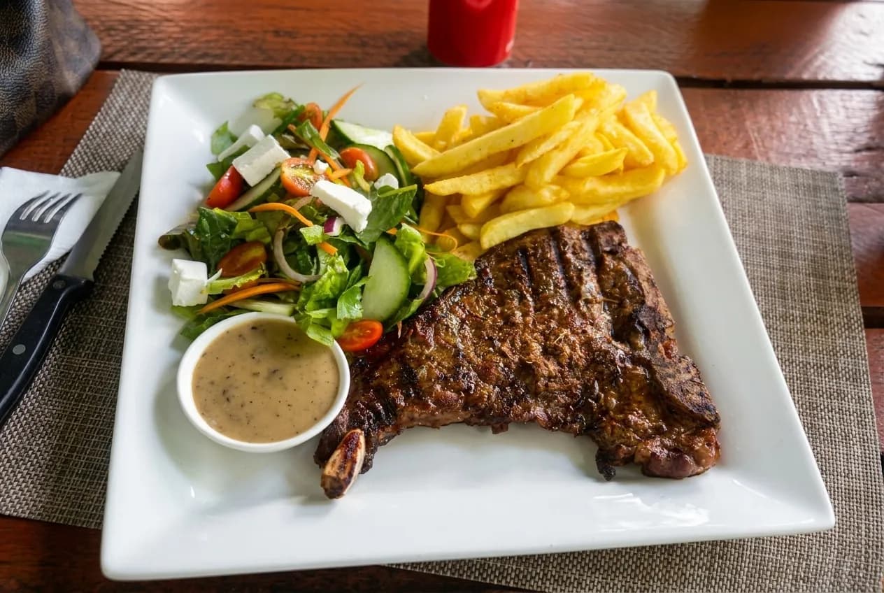 A steak and salad on a plate under warm restaurant light