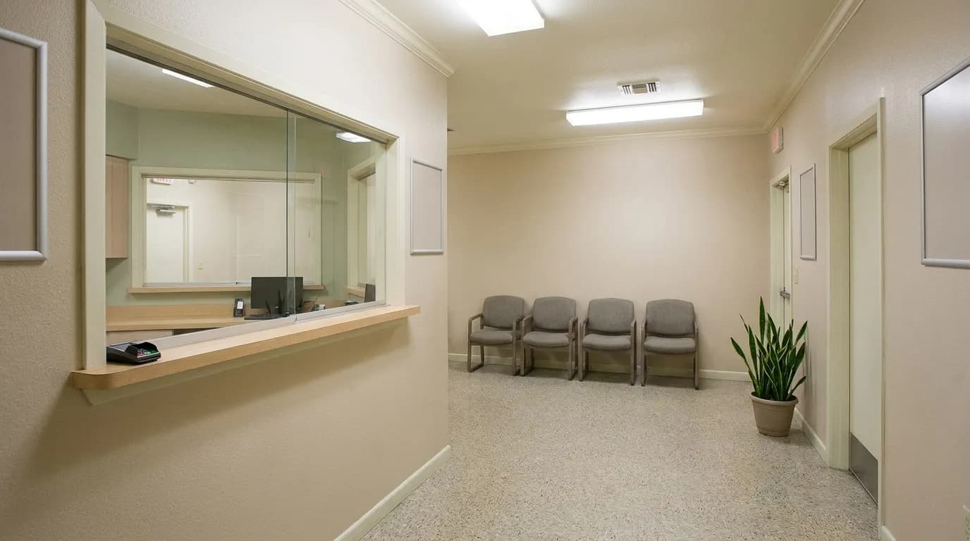 A clean retail interior with a reception desk, waiting chairs and a closed inner door