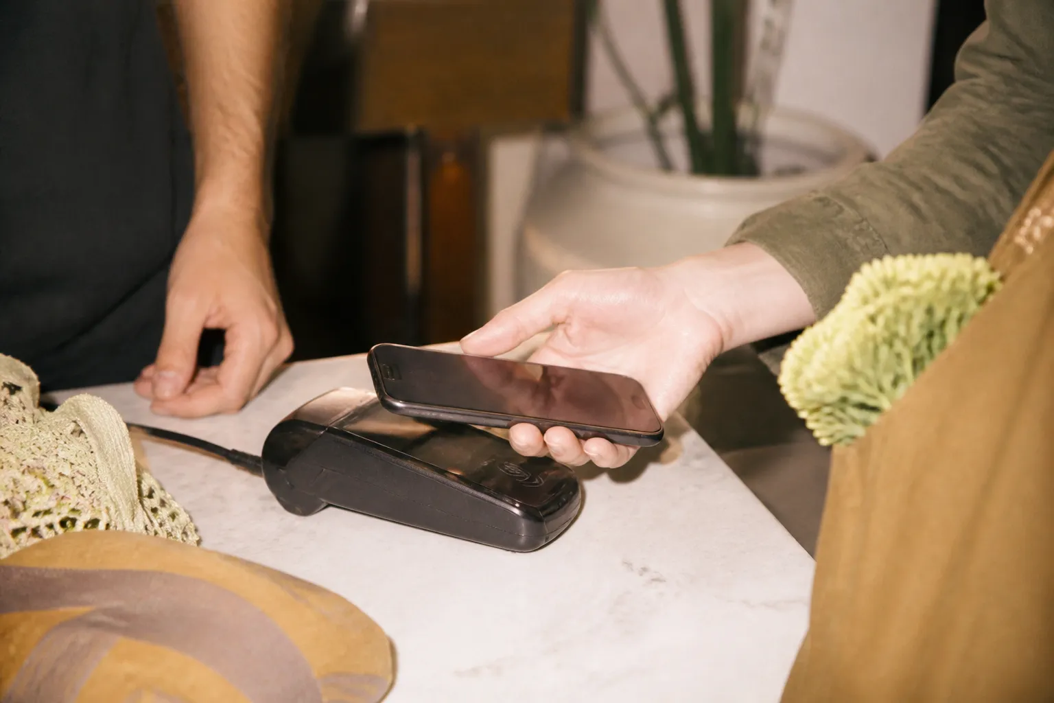 A phone hovering over a contactless card reader at a store checkout