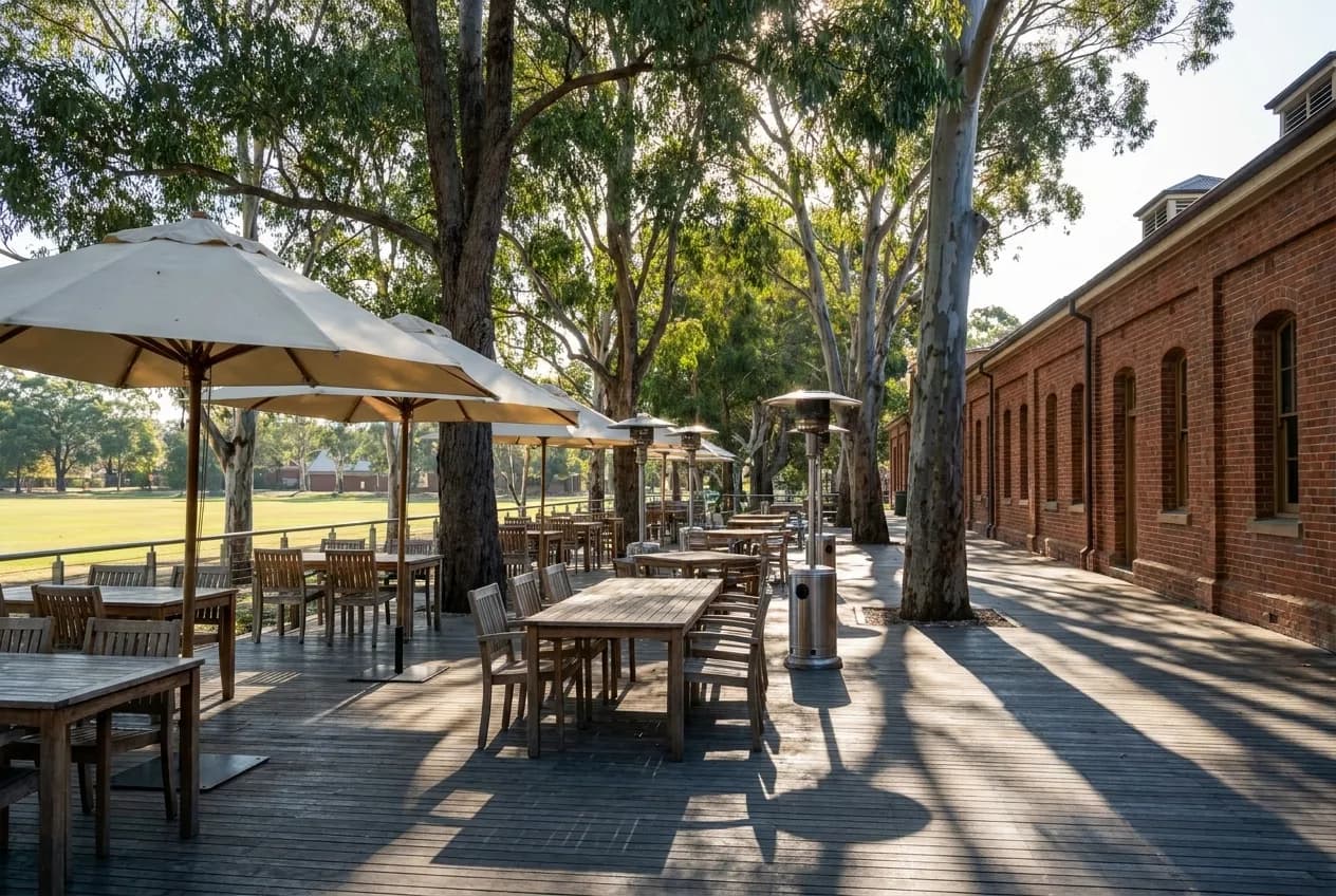 A large heated restaurant terrace among eucalyptus trees with a parade ground beyond
