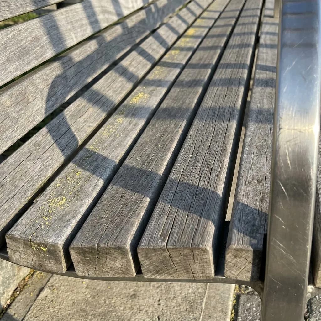 England's Three Lions in New Jersey: The Team Hotel Corridor from Weehawken to Hoboken — Tactile detail of weathered teak bench slats on the Hoboken waterfront walkway,