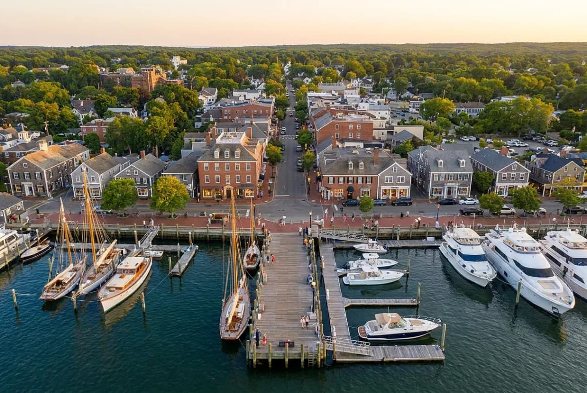 A historic whaling-village waterfront street with a wharf and boats on a warm summer evening