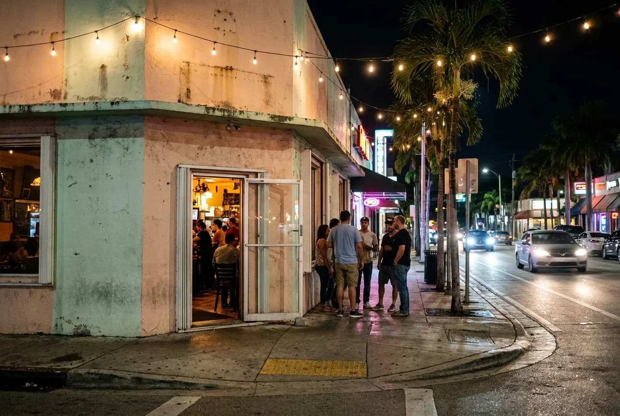 Night exterior of a Little Havana restaurant with string lights, pastel-painted facade, open doors spilling warm light, and a small crowd gathered near the entrance.