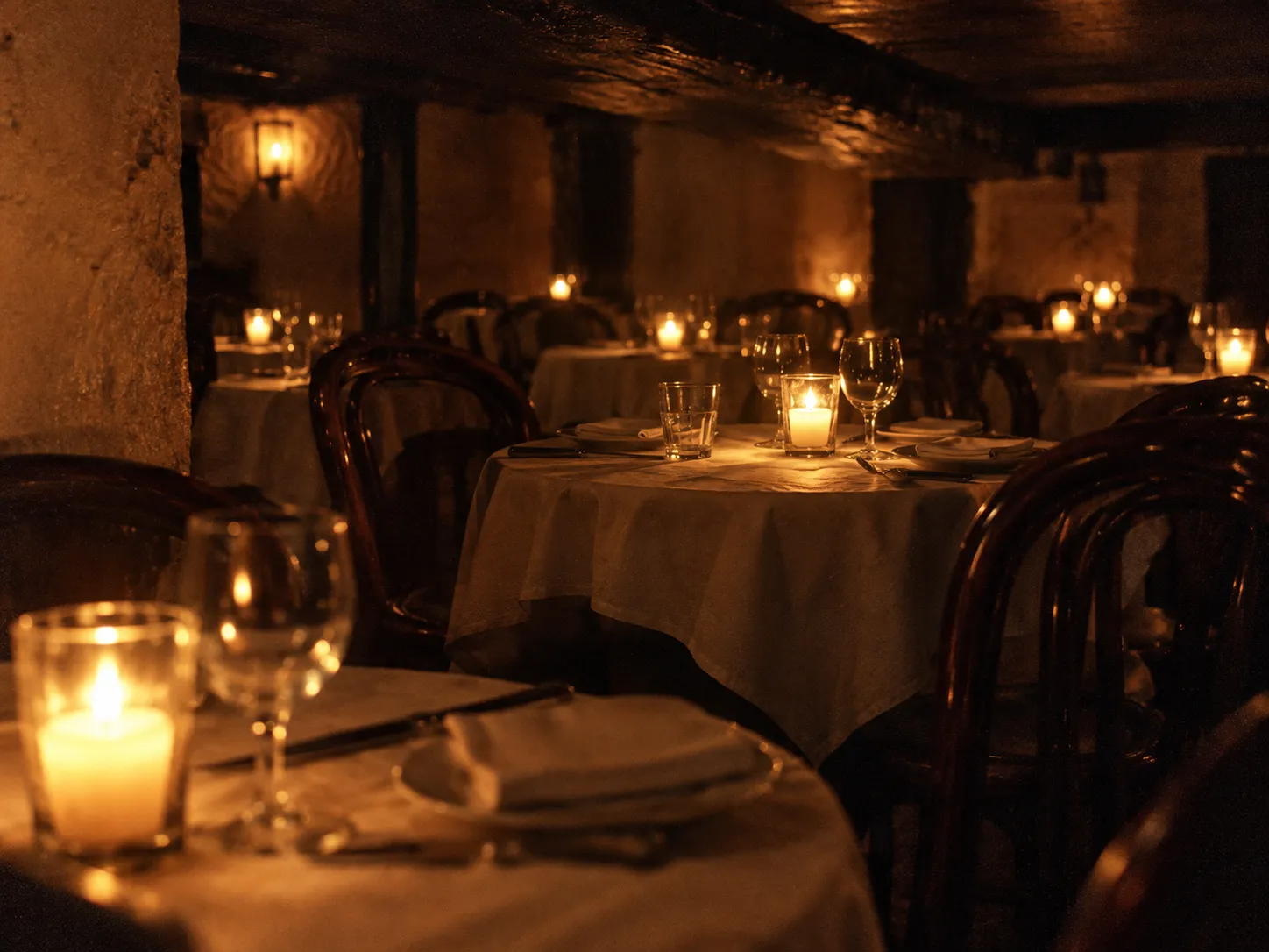 Closely packed small round tables with candles in a dark low-ceilinged room