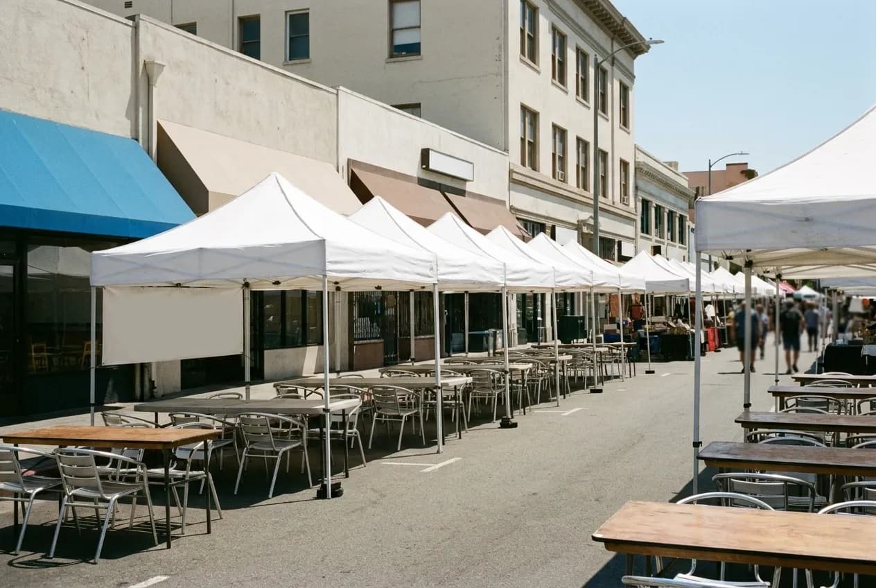 Rows of white vendor canopies across an open lot under bright daylight