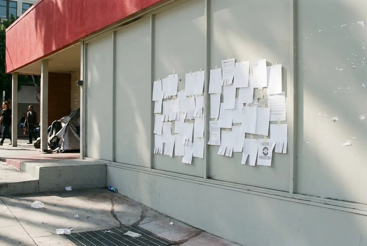 A community noticeboard covered with blank paper flyers