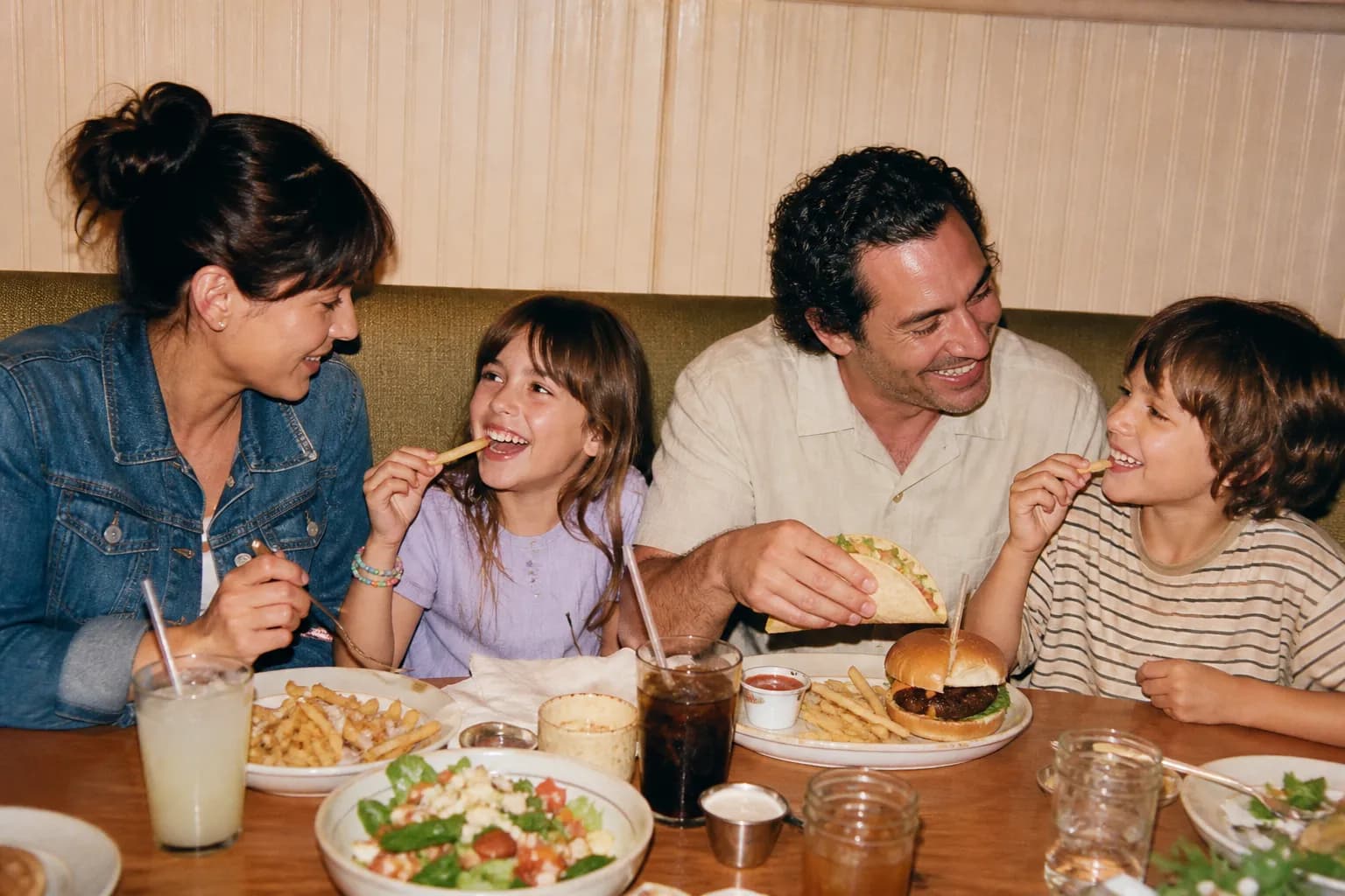 A bright family-friendly restaurant booth with a shared meal on the table