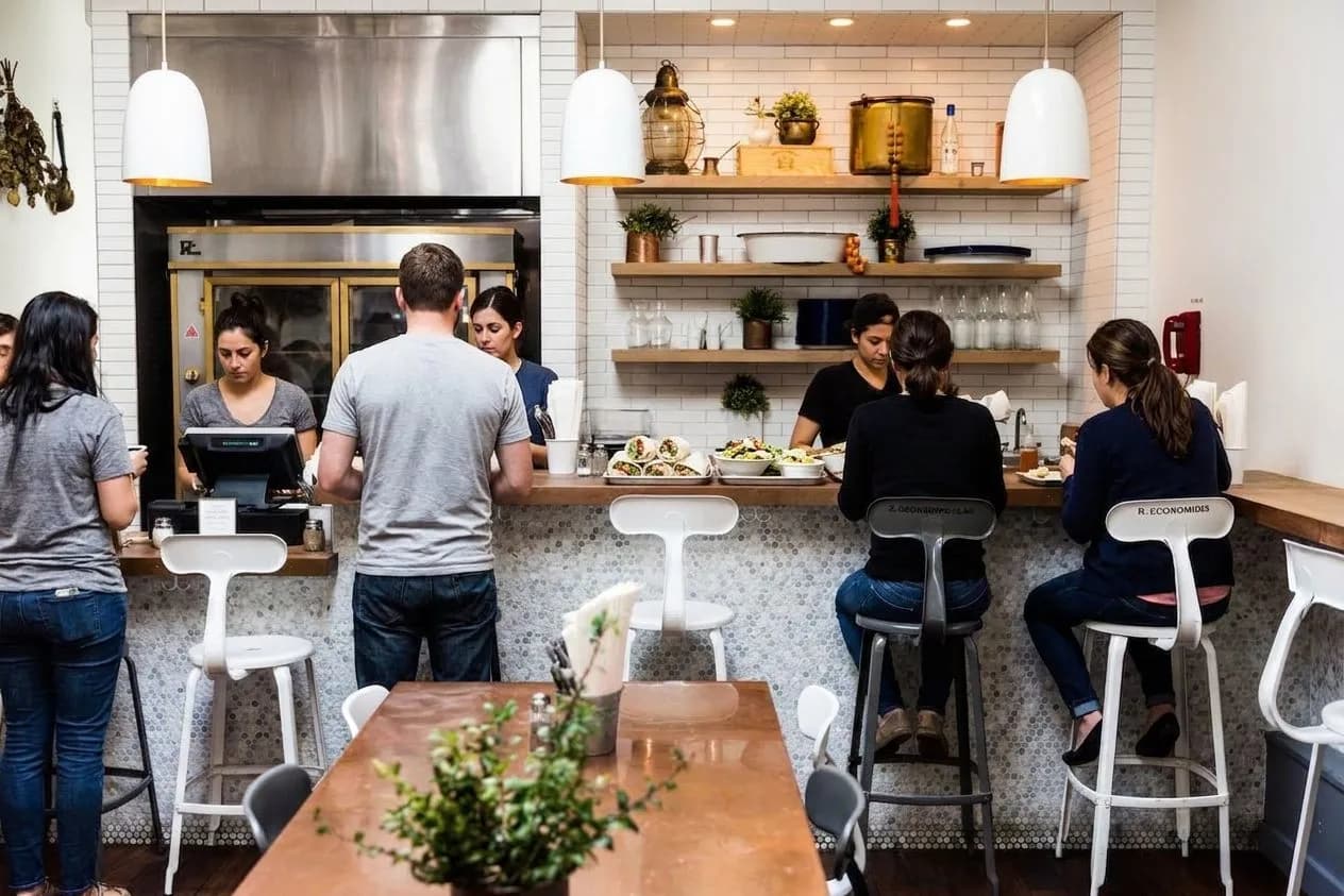 Fast-casual Greek lunch counter with trays and diners ordering in San Francisco