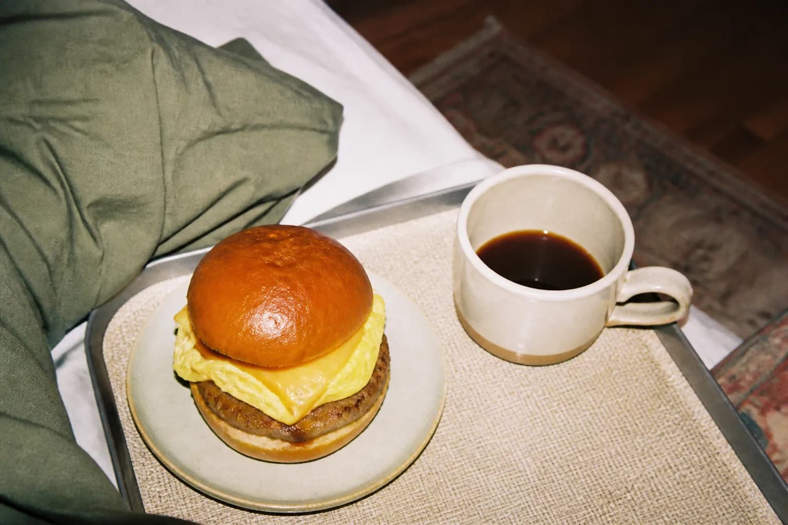 A warm breakfast sandwich beside a cup of coffee on a fast food tray