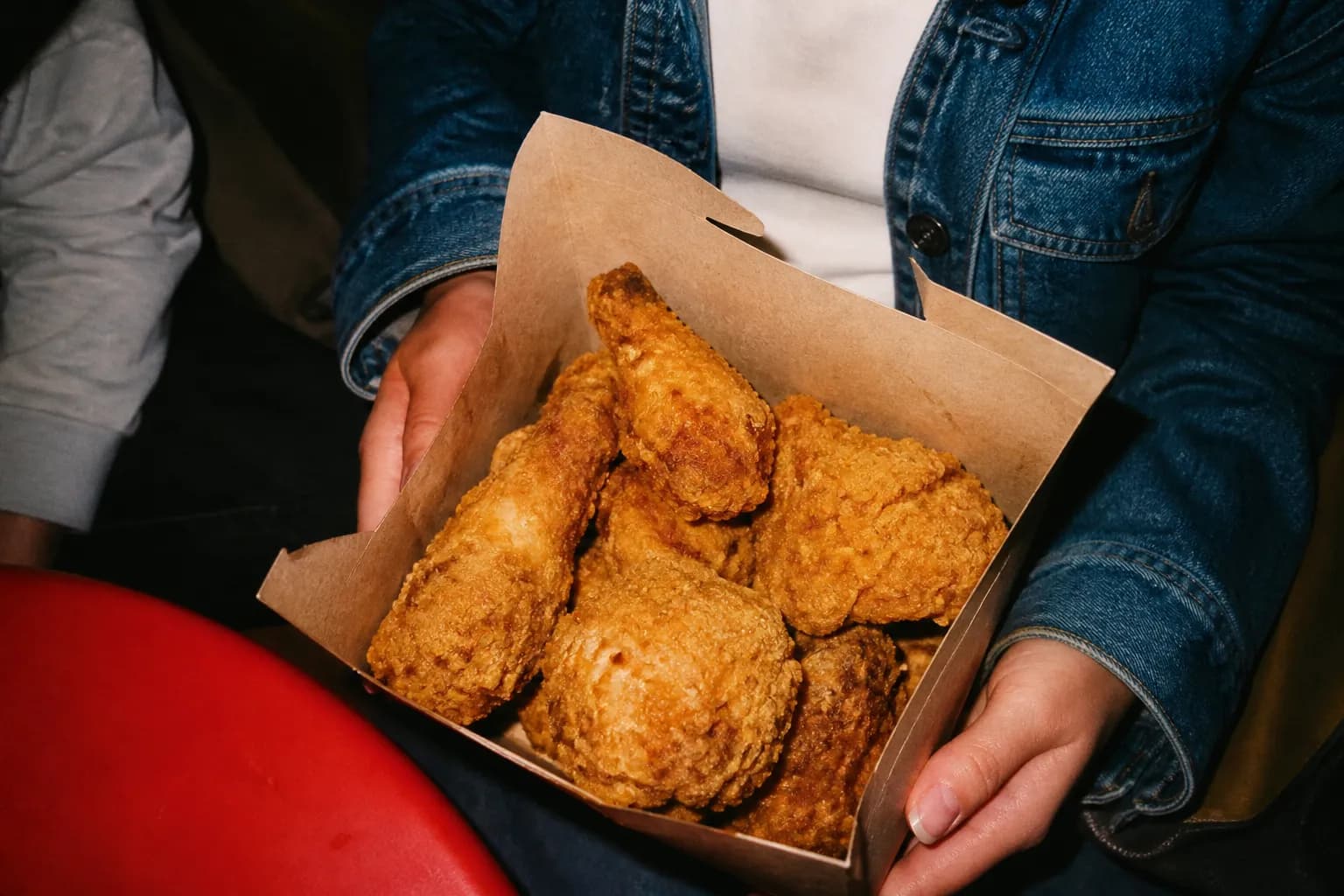 Crispy fried chicken pieces arranged in a paper takeout box