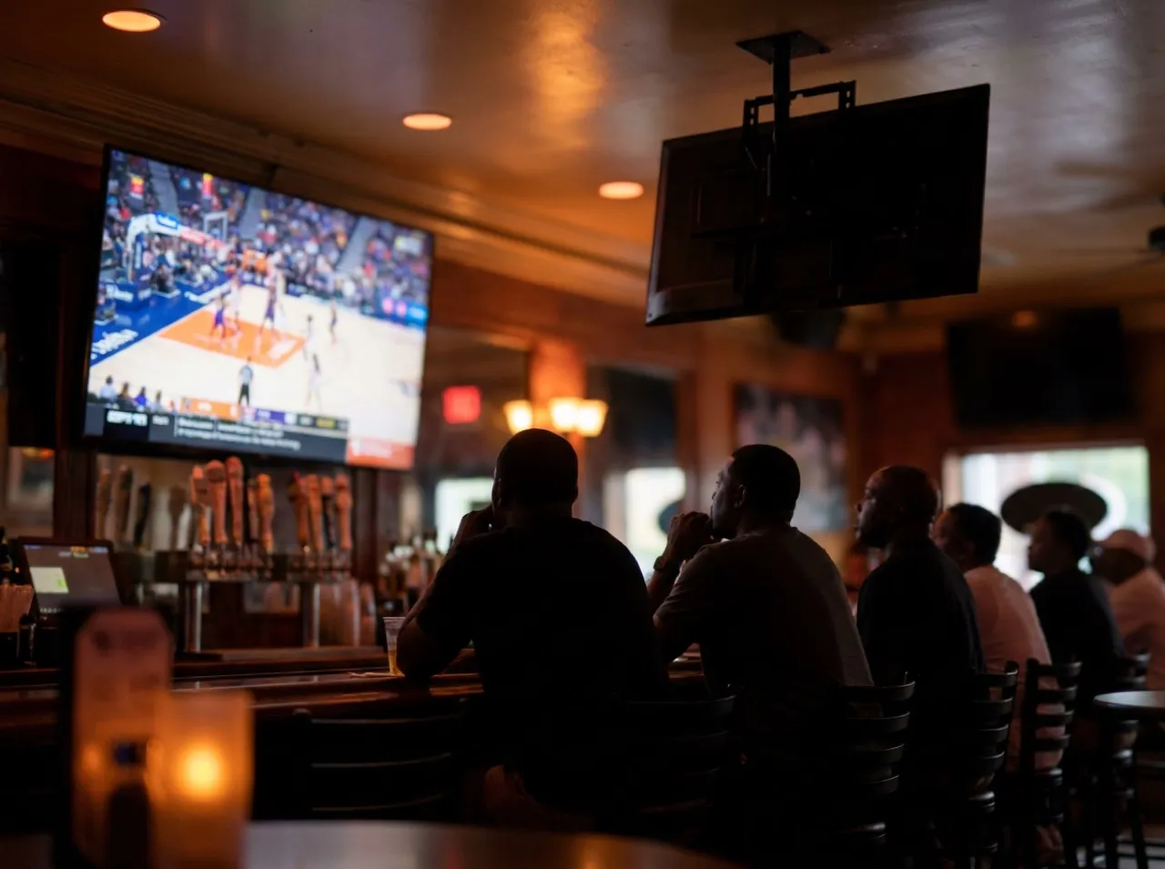 Interior of a Downtown LA sports bar with patrons watching a basketball game on mounted screens