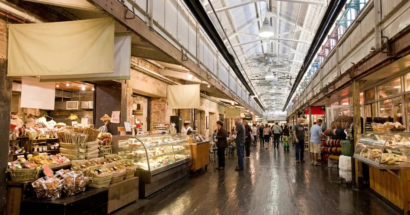 Food counters and pastry cases lining the brick concourse inside a Chelsea Market style food hall in New York