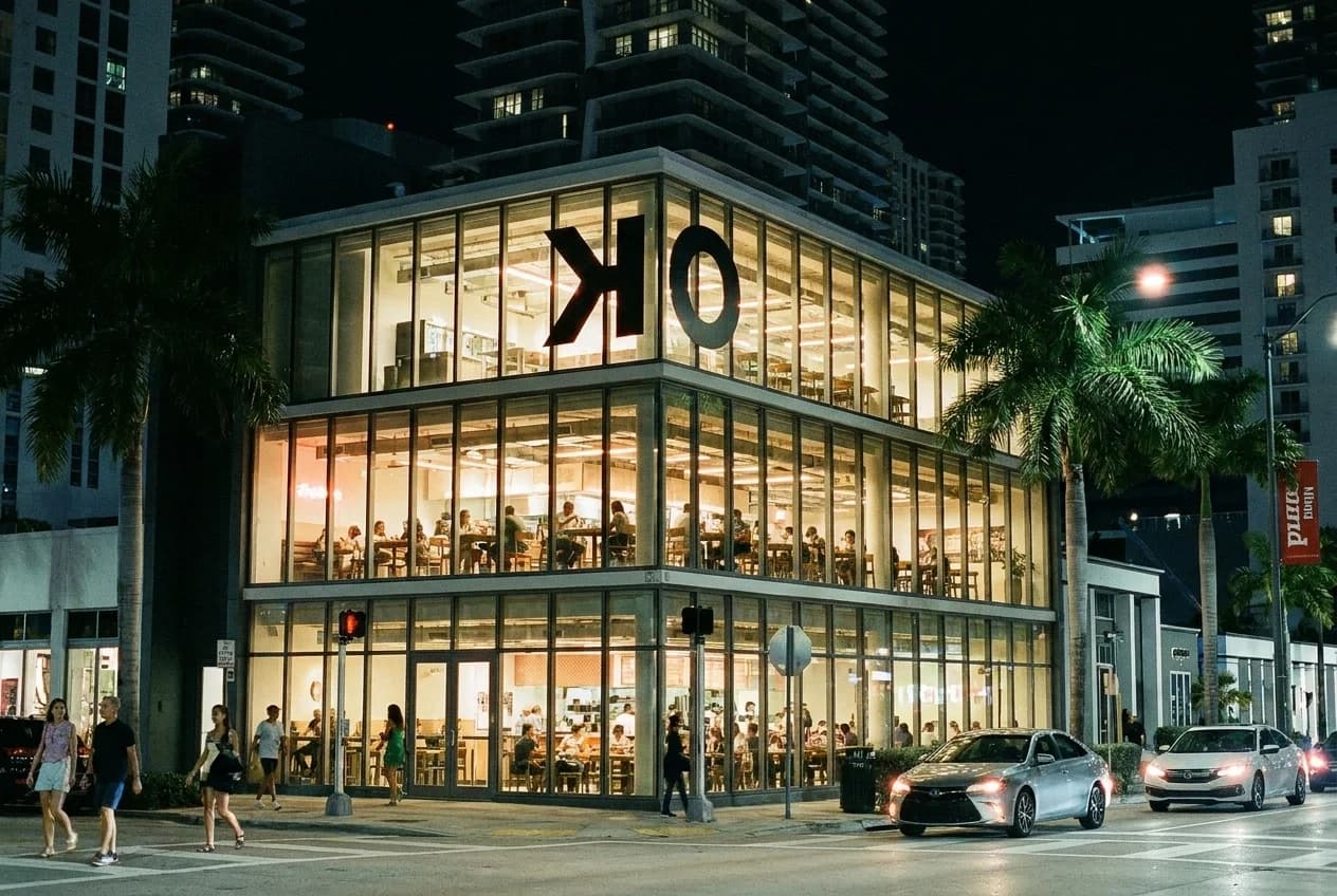 Okeydokey food hall exterior at night on SW 8th Street in Brickell, glass facade lit with communal dining visible inside