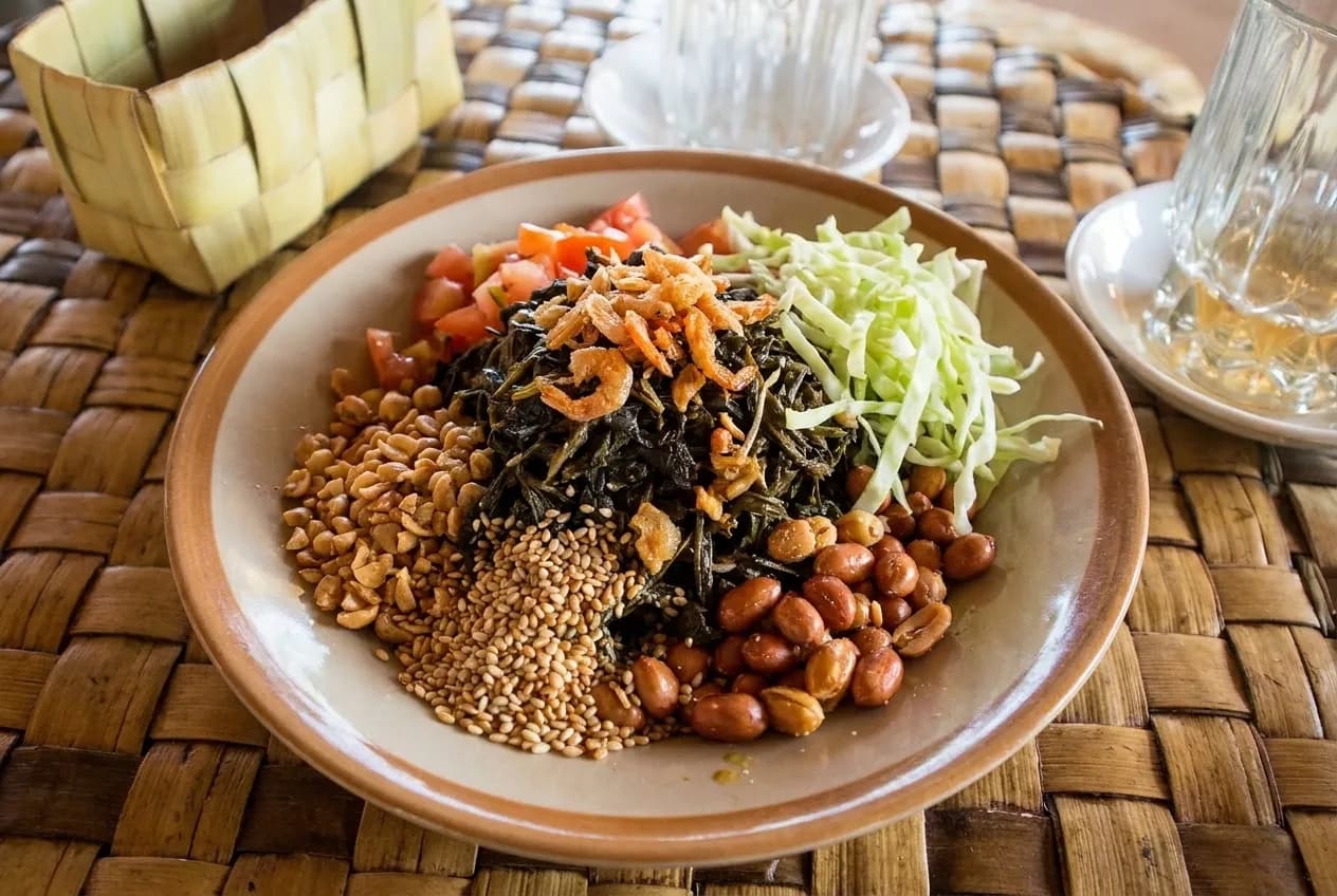 A plate of fermented tea leaf salad with peanuts, tomato and shredded cabbage