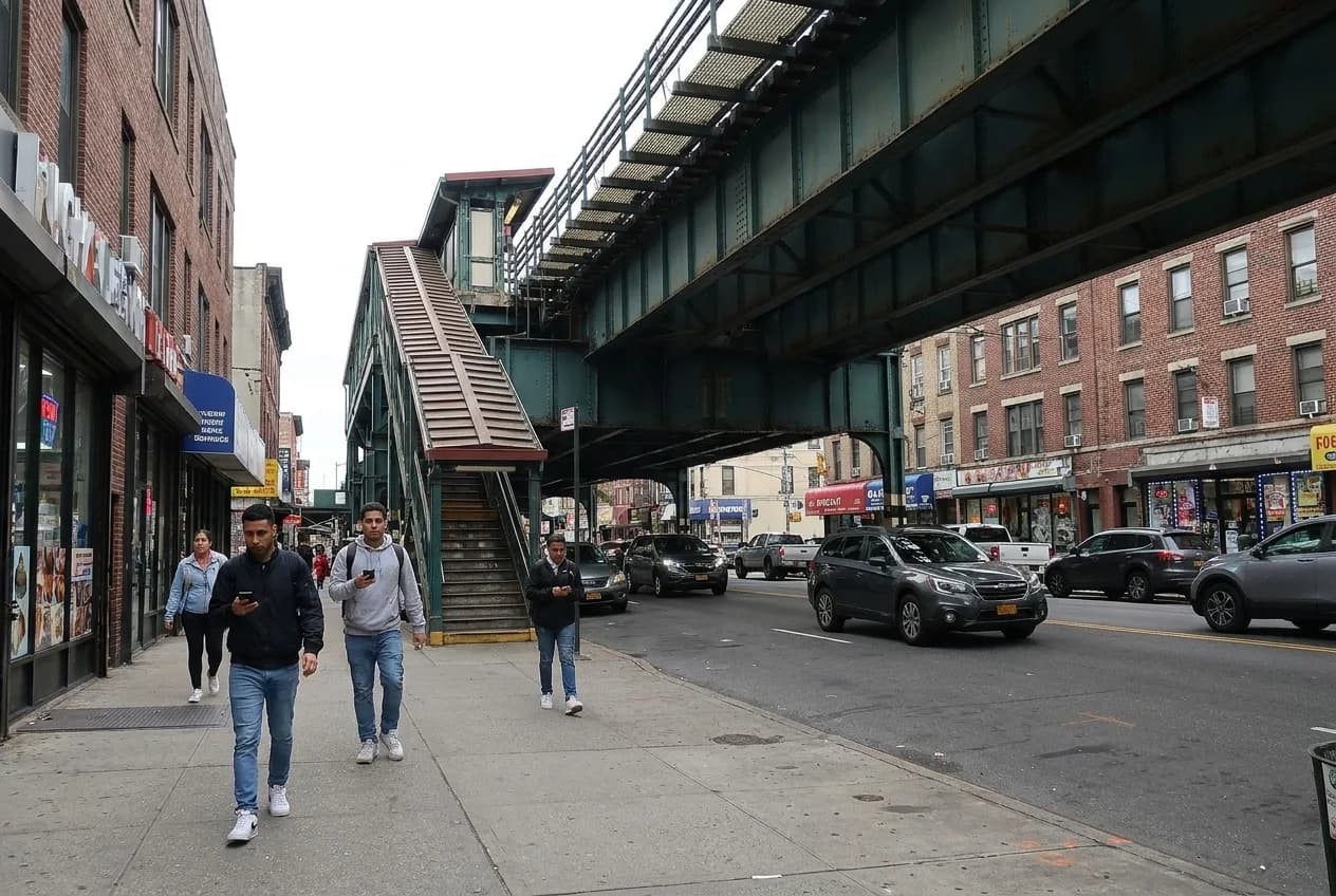 Elevated J and M train tracks over Broadway in Williamsburg with station stairs and storefronts below
