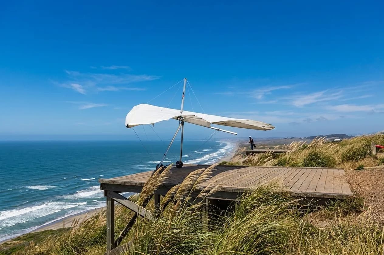 Hang glider preparing for launch on clifftop platform at Fort Funston with coastal views