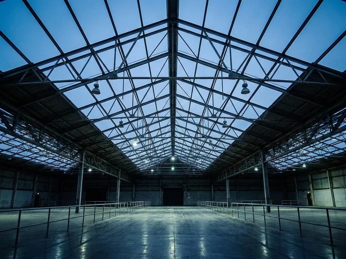 A wide museum hall with high steel roof trusses and dim lighting seen from a low angle