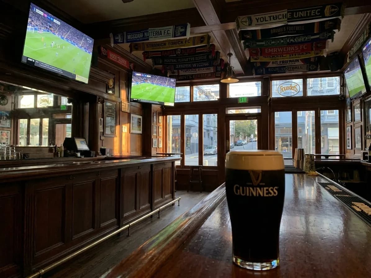 Interior of Danny Coyle's pub in San Francisco's Haight district, showing soccer scarves hanging from ceiling and HD screens displaying match coverage