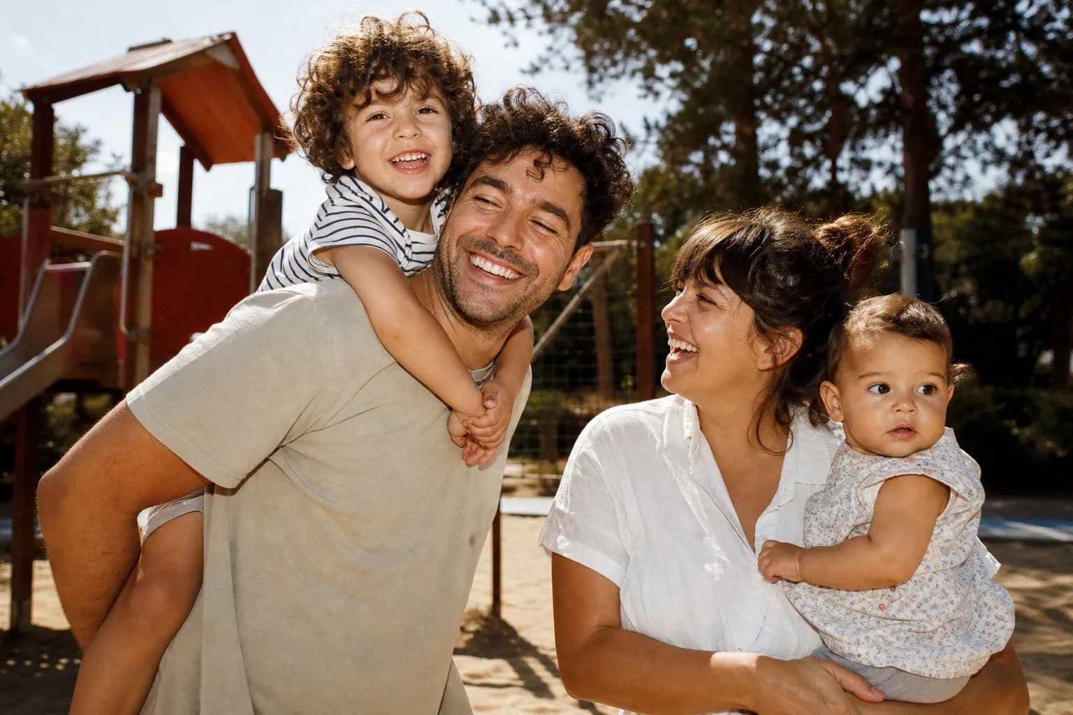 A family enjoying a bright playground with climbing frames on a sunny day