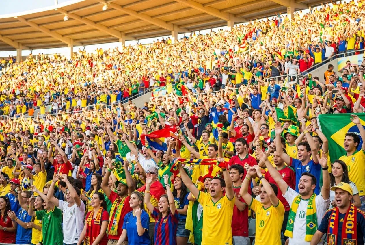 Packed Arrowhead Stadium bowl roaring under bright lights with thousands of colorful fans creating waves of sound during a World Cup knockout match
