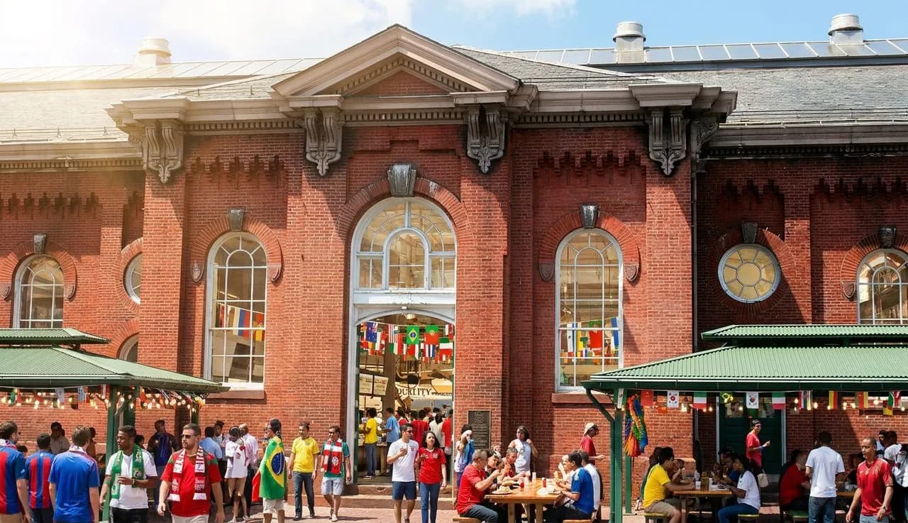 A vibrant Atlanta food hall interior full of stalls and diners under bright natural light, with World Cup scarves and jerseys adding festive color to the bustling scene