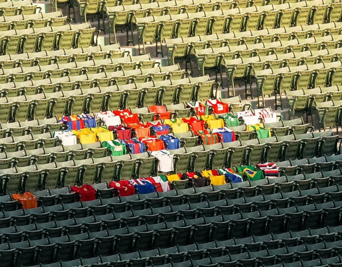 Stadium seating bowl divided between shaded upper sections and sun-drenched lower rows on a clear day
