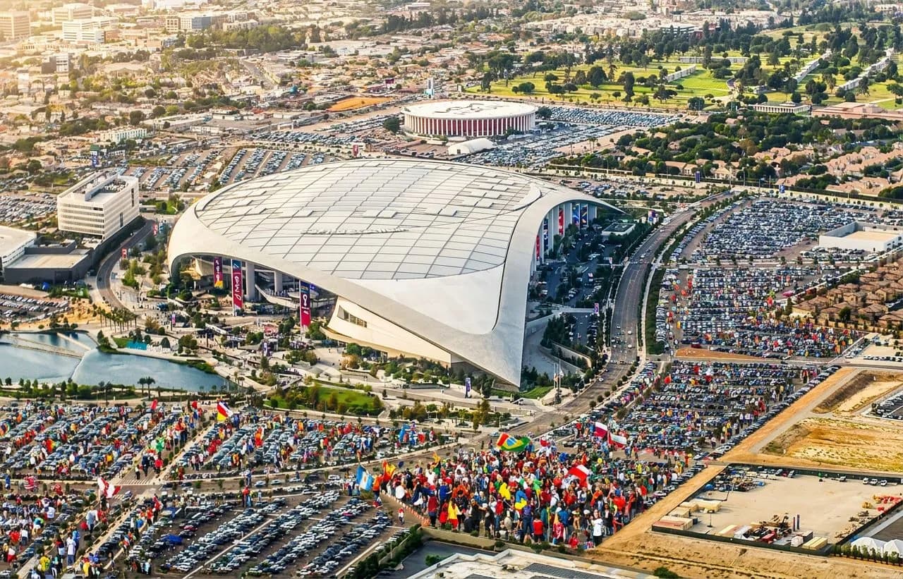 Aerial view of sprawling stadium parking lots under bright sunshine, scattered jerseys and scarves adding festive World Cup color