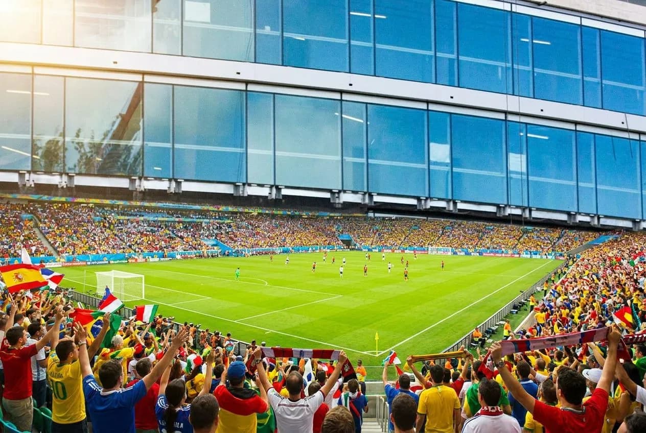 Wide view of a sunlit World Cup pitch mid-match with players in motion, fans filling the stands in vibrant blue and red