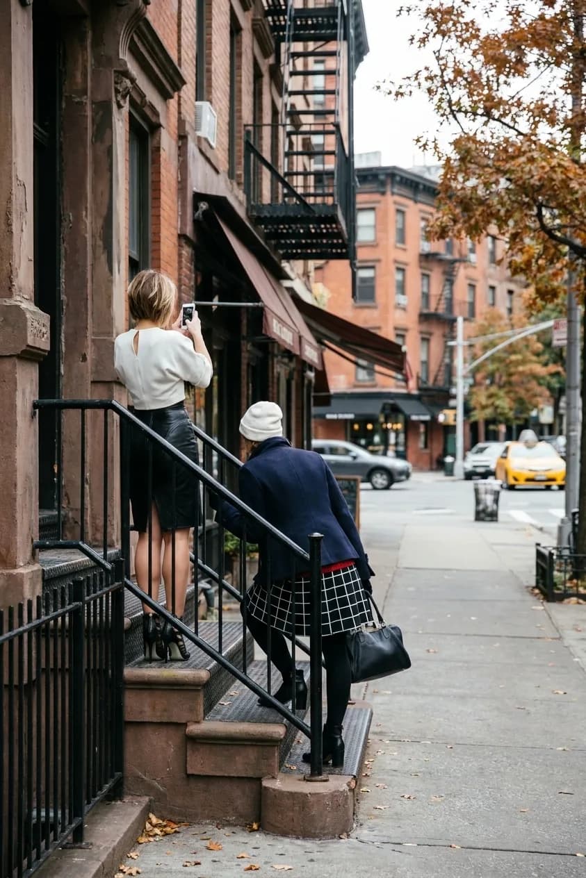 A New York street of brownstones and storefront awnings in autumn light