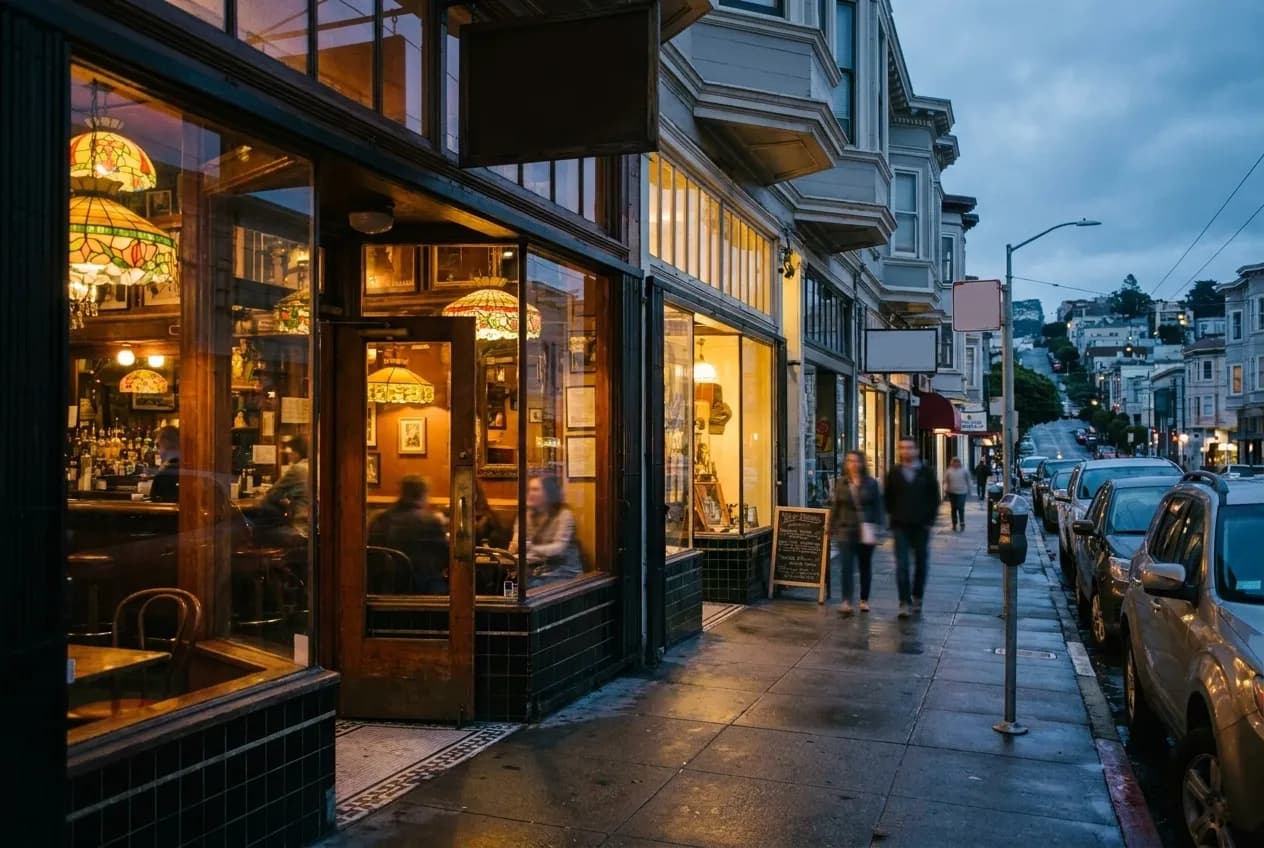 A San Francisco street in North Beach at dusk with pedestrians and warm storefront light.