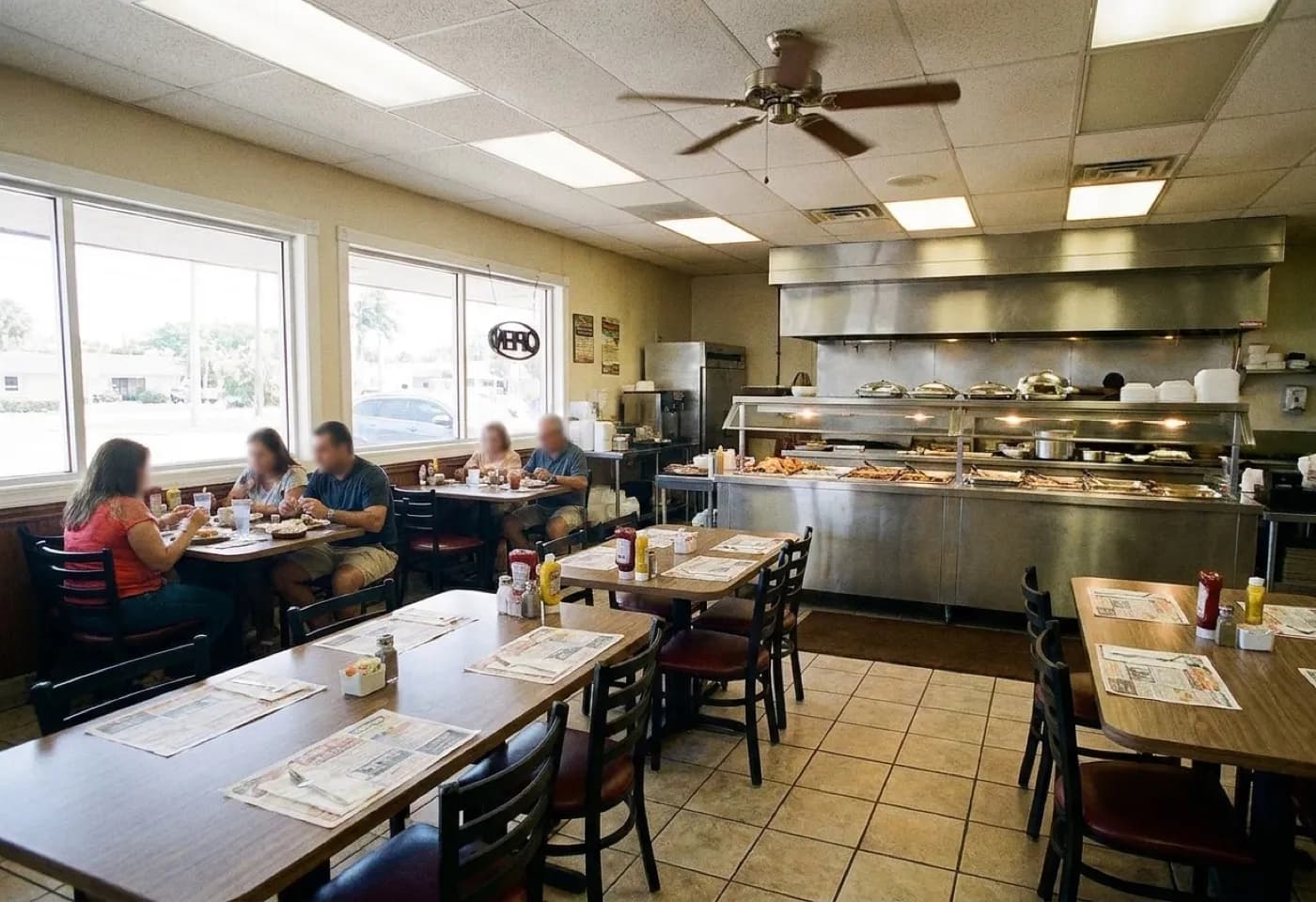 A modest Cuban restaurant dining room in daylight with tiled floors, laminate tables, a service counter at the back and a few occupied tables