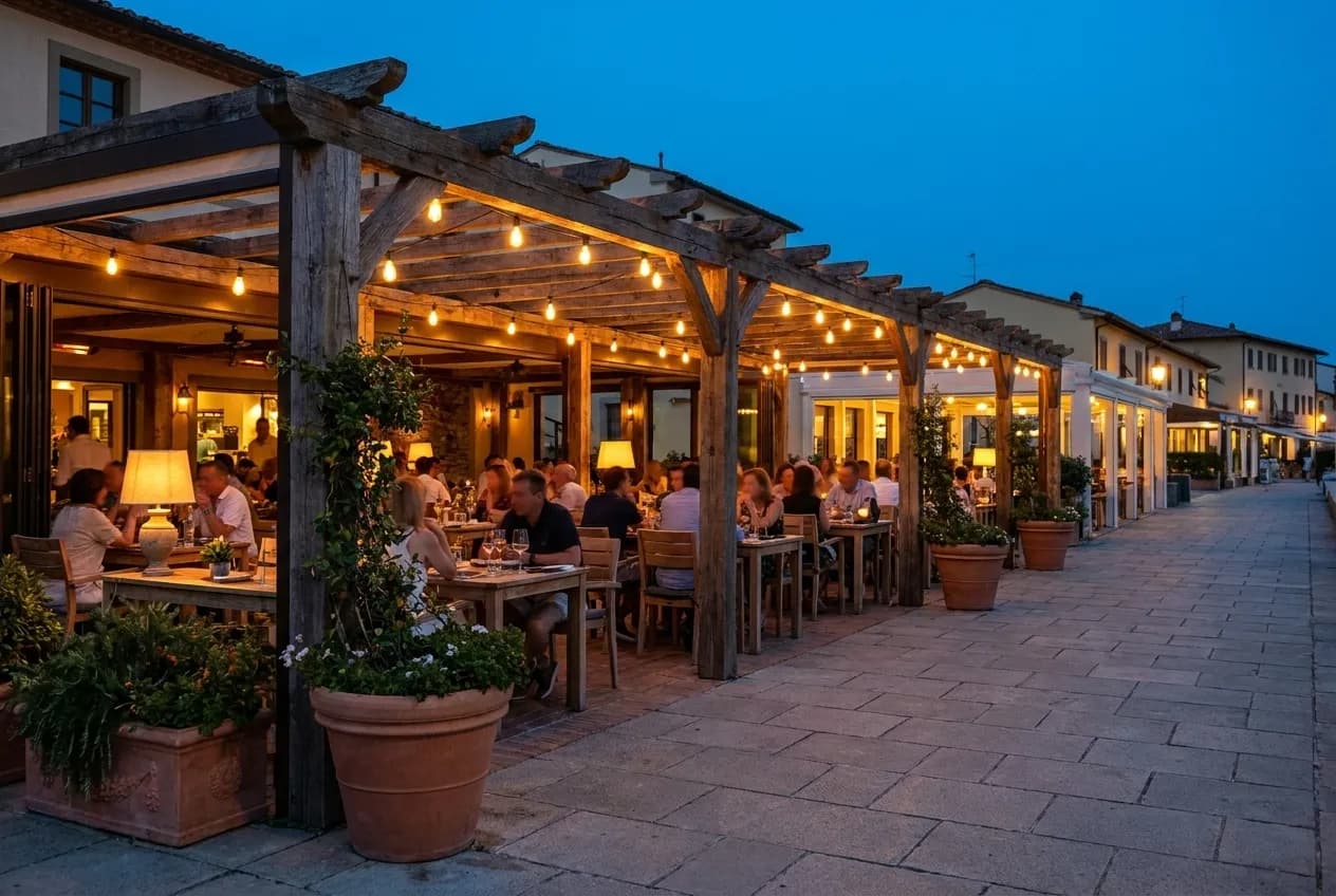 A covered outdoor patio on a pedestrian promenade with string lights at dusk