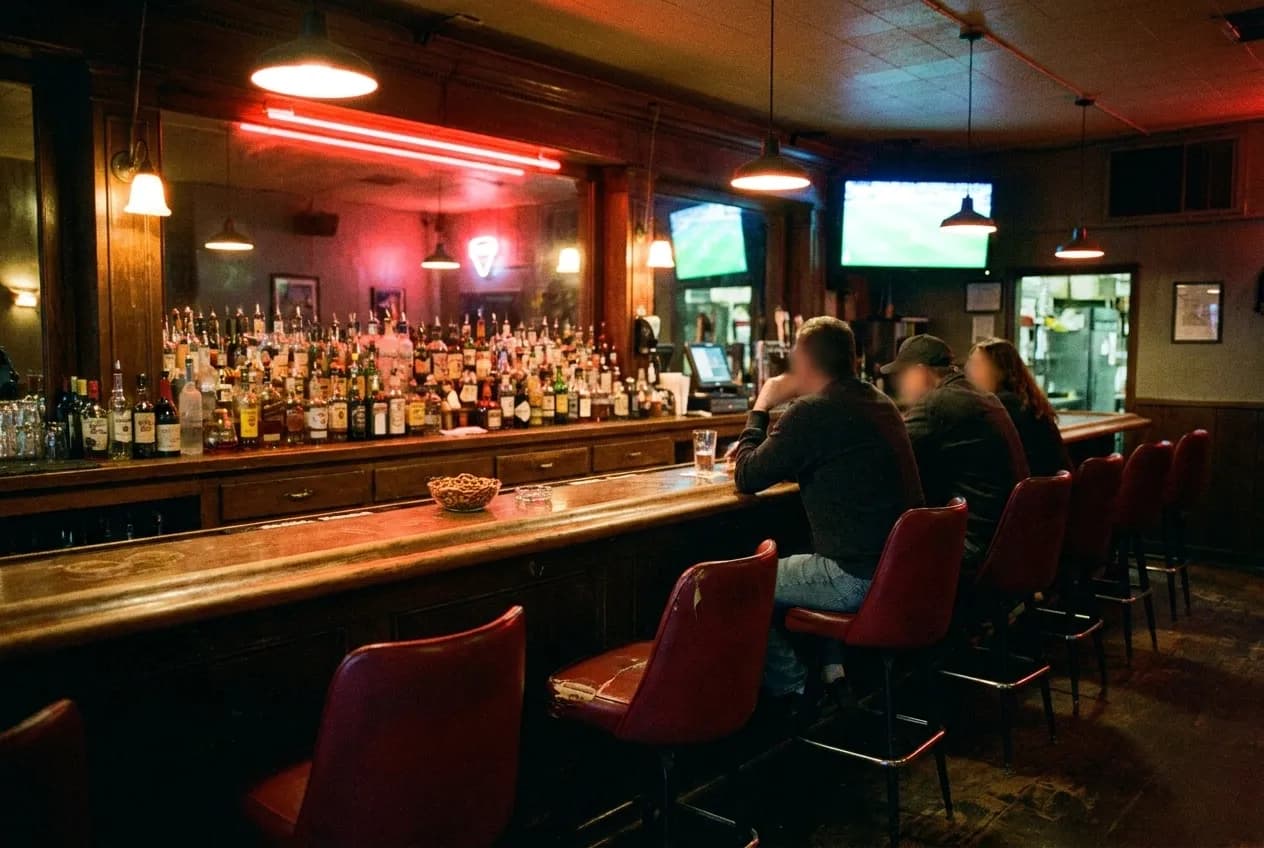 A dark Los Angeles bar interior with screens on and a few people at the counter