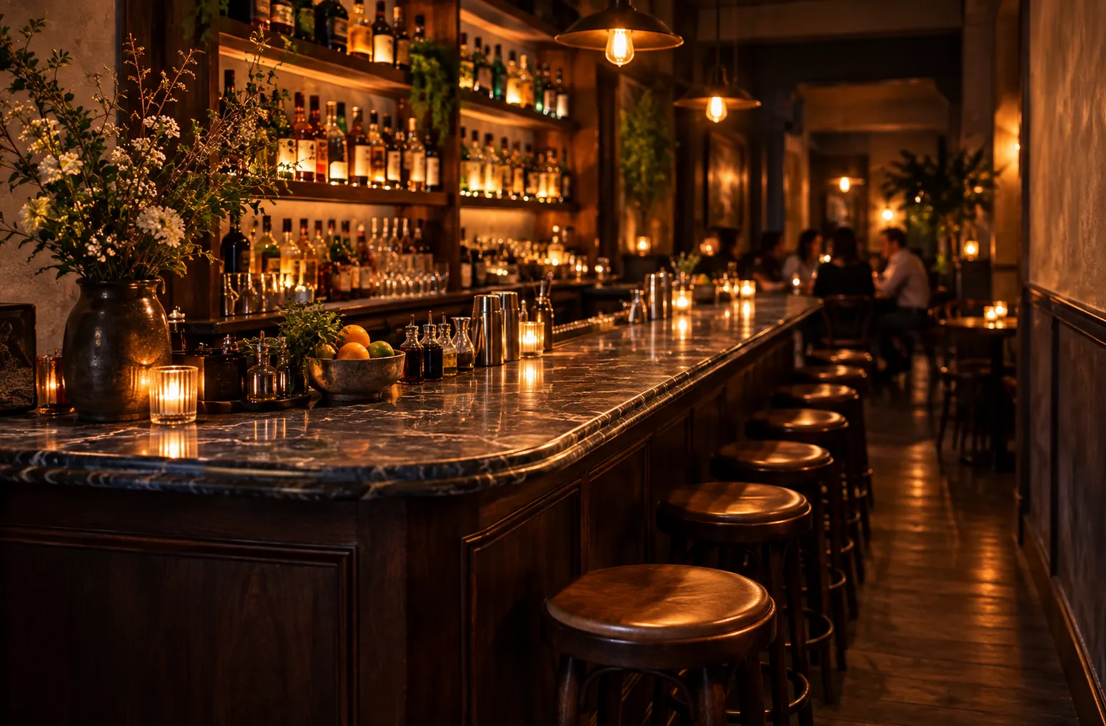 A small dimly lit cocktail bar with a marble bar top, wooden stools and shelves of bottles