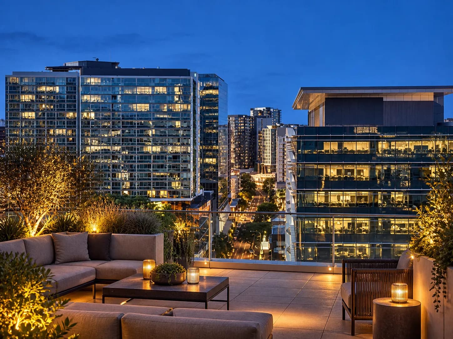 A rooftop terrace at dusk with low seating and a city skyline behind