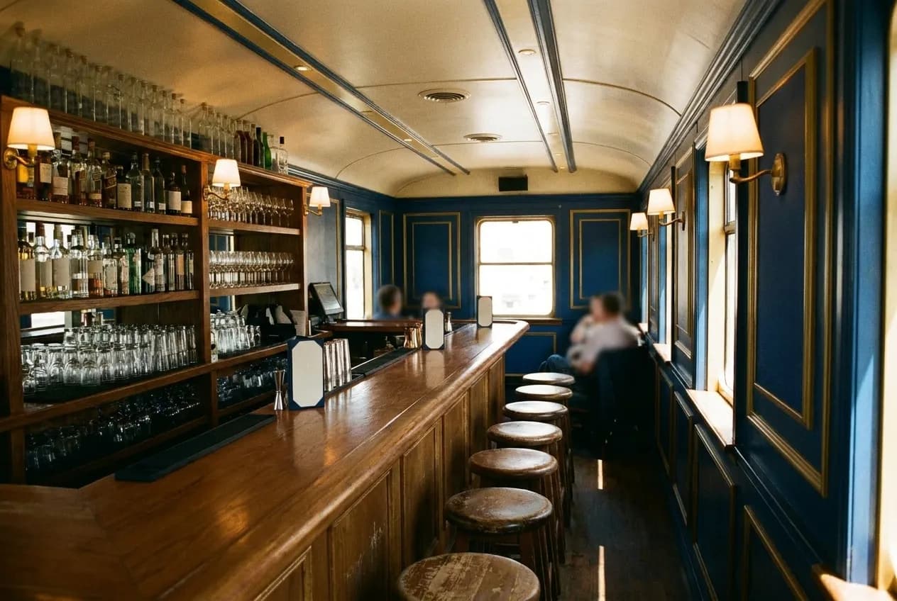 A narrow bar interior with warm lamps, bottles and a row of stools in Los Angeles