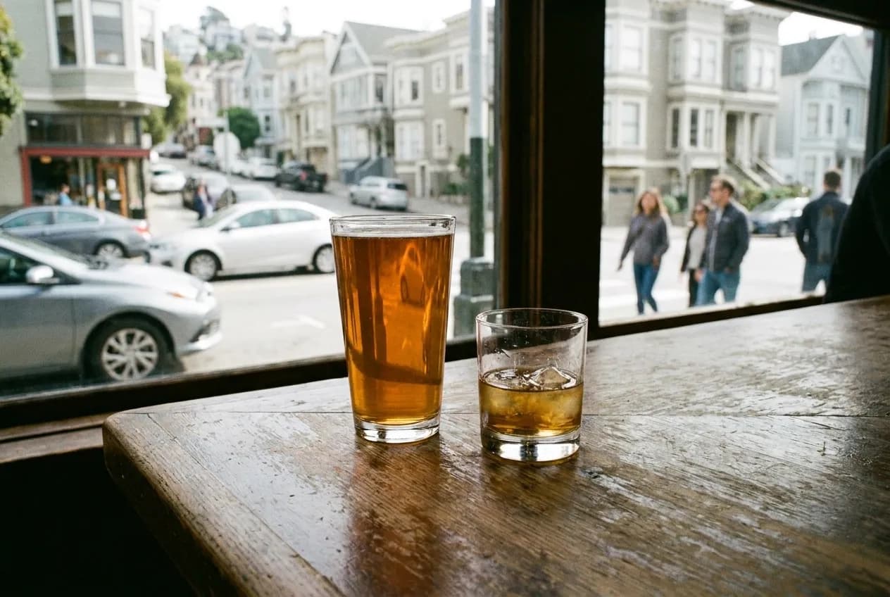 A beer and a whiskey glass side by side on a wooden bar