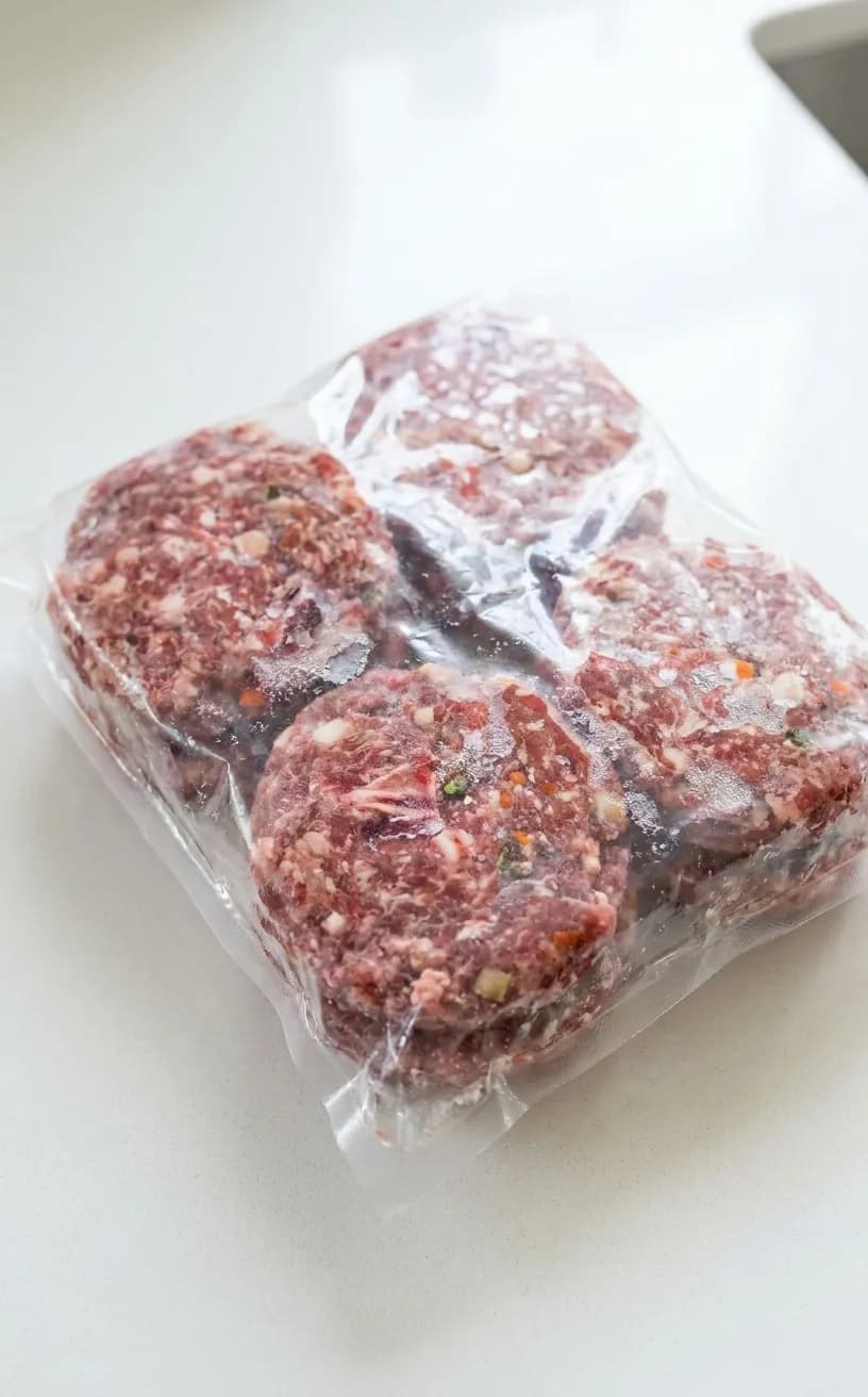 Frozen raw dog food patties in clear packaging showing meat texture and ingredient transparency
