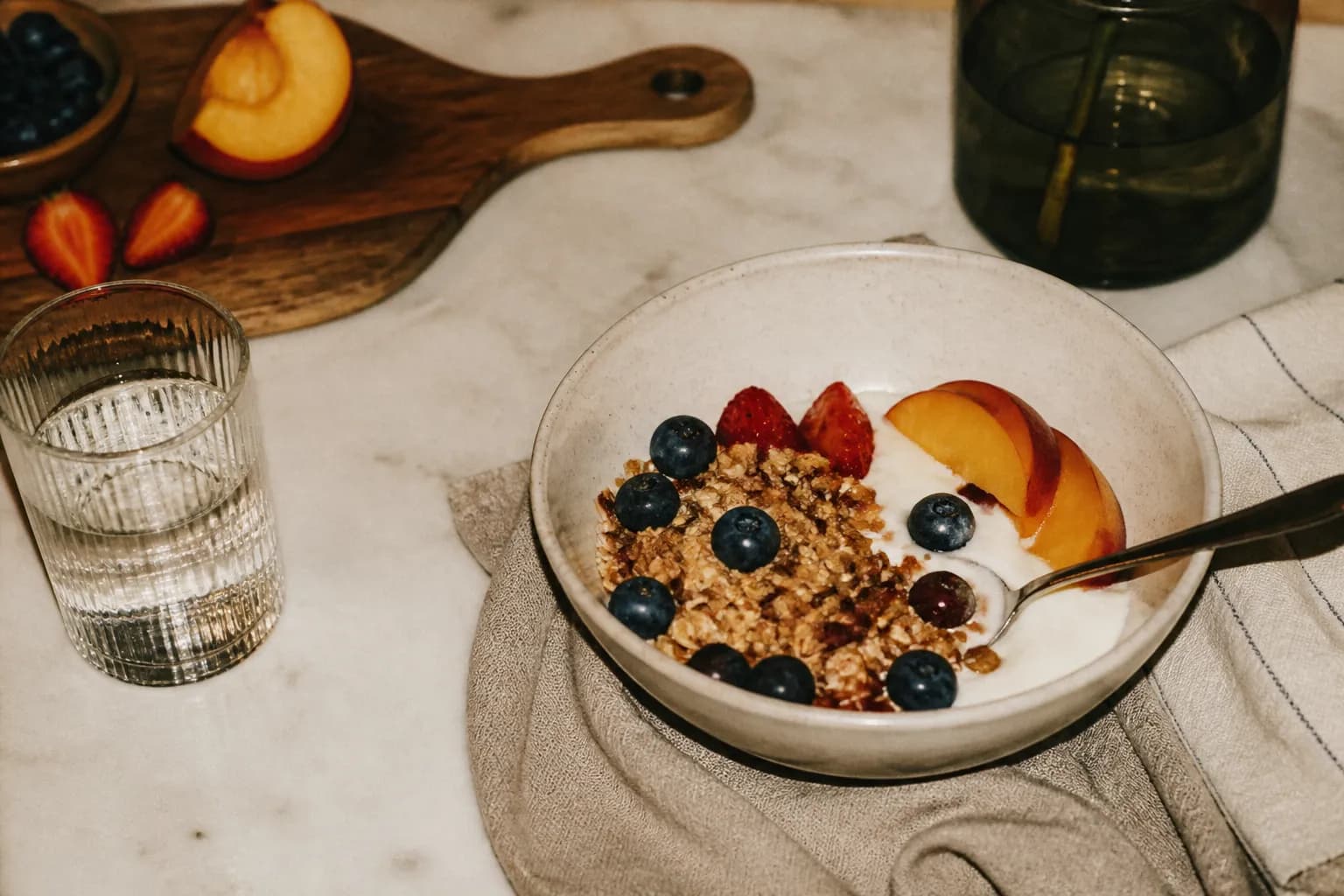 A yogurt and fruit bowl topped with granola on a bright table
