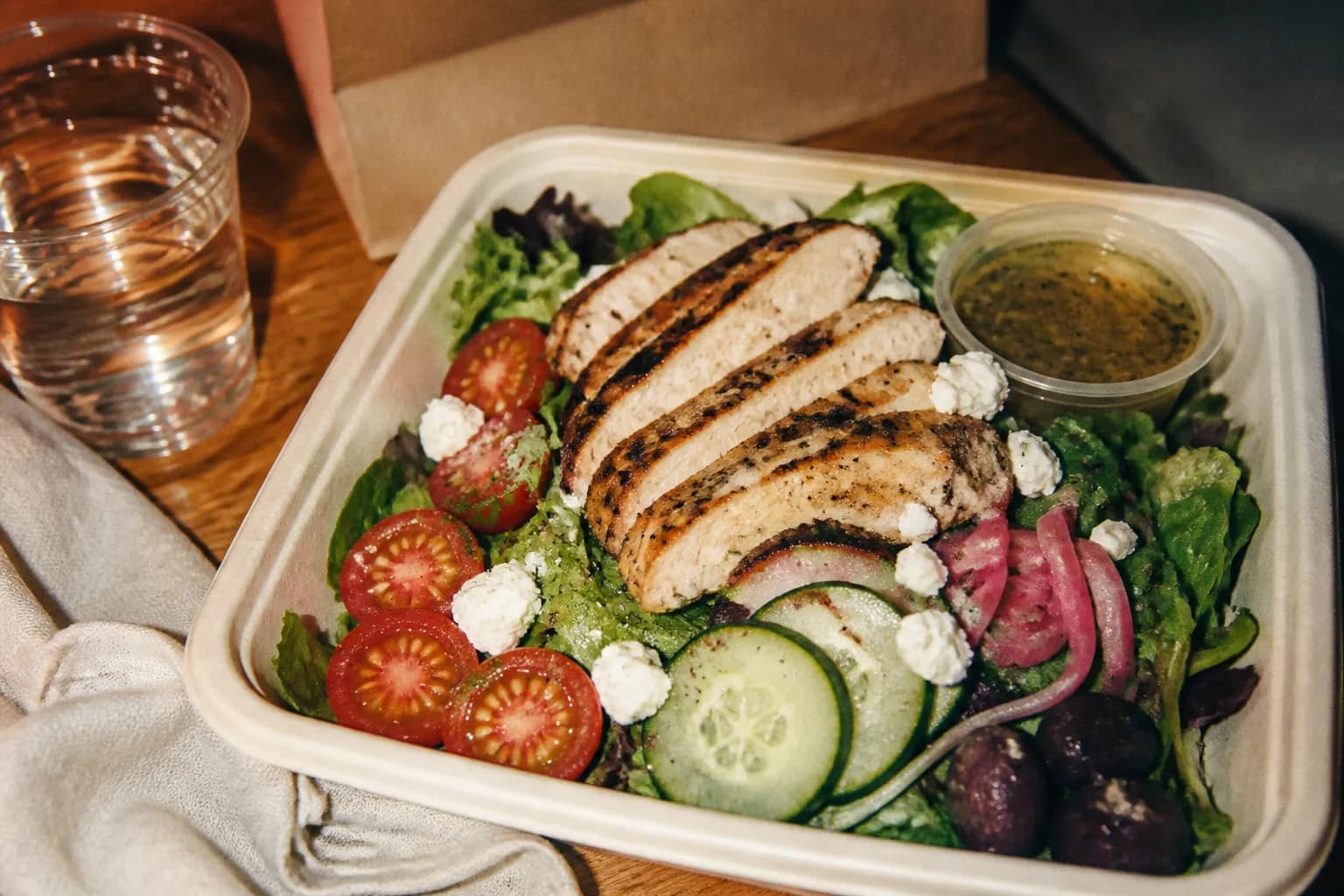 A fresh grilled chicken salad served in an eco-friendly to-go bowl