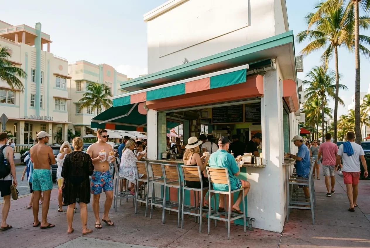 A busy walk-up sandwich counter with outdoor seating in South Beach on a sunny afternoon