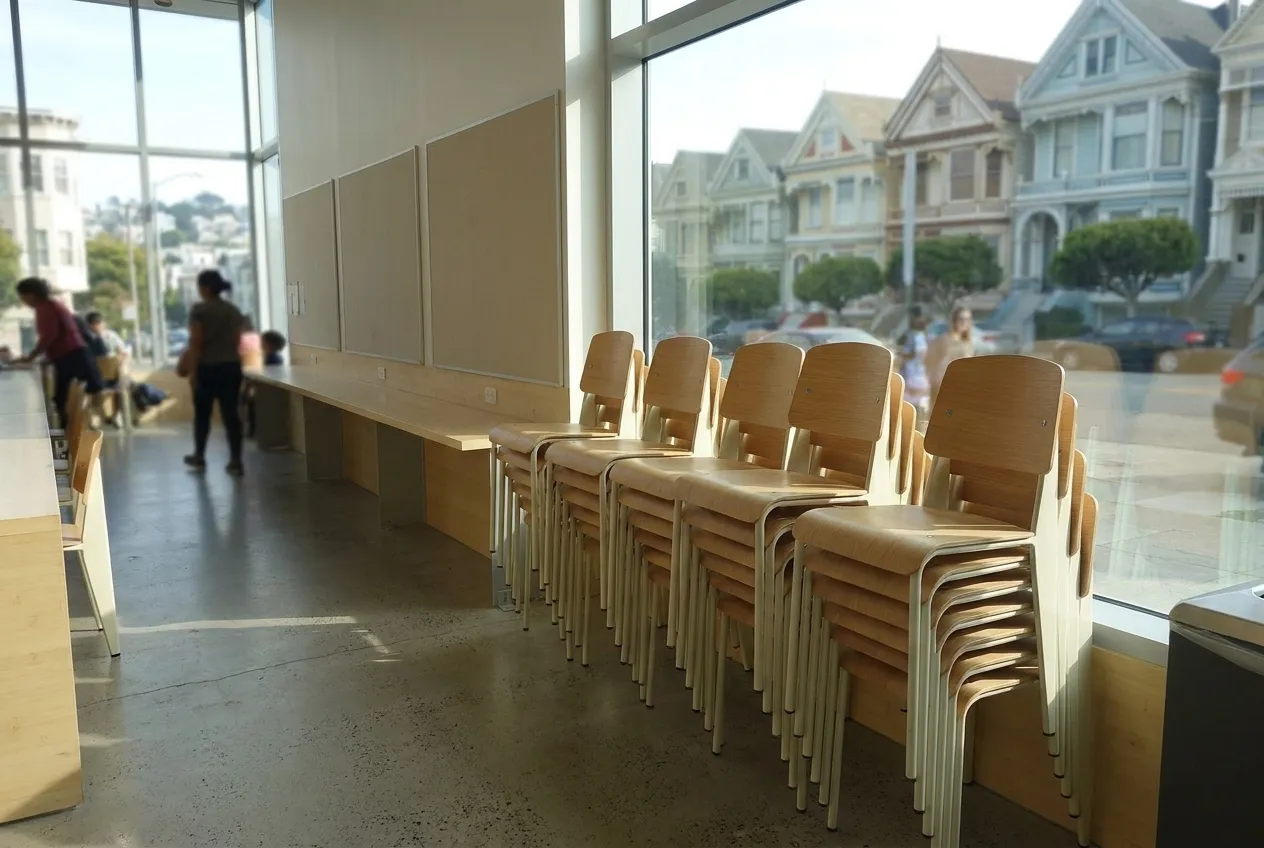 A community hall interior with stacked chairs and a wide window