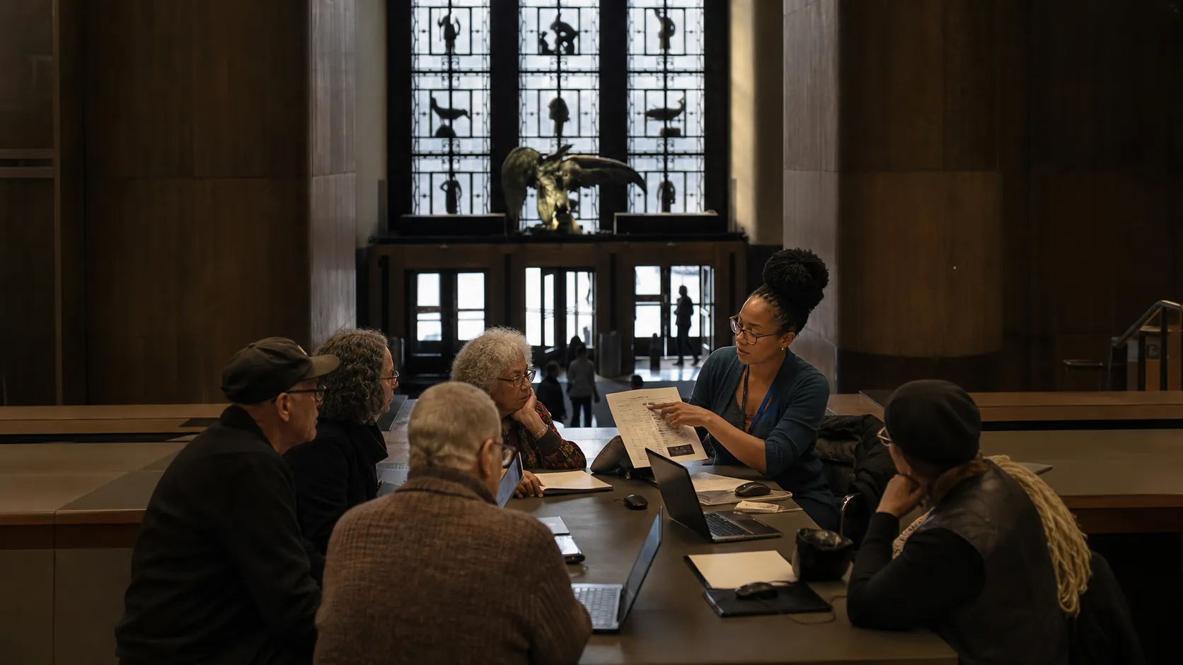 A small beginner technology workshop meets around laptops inside a Brooklyn public library space.
